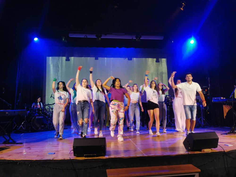 Jugendliche und Musikgruppe tanzen auf Bühne