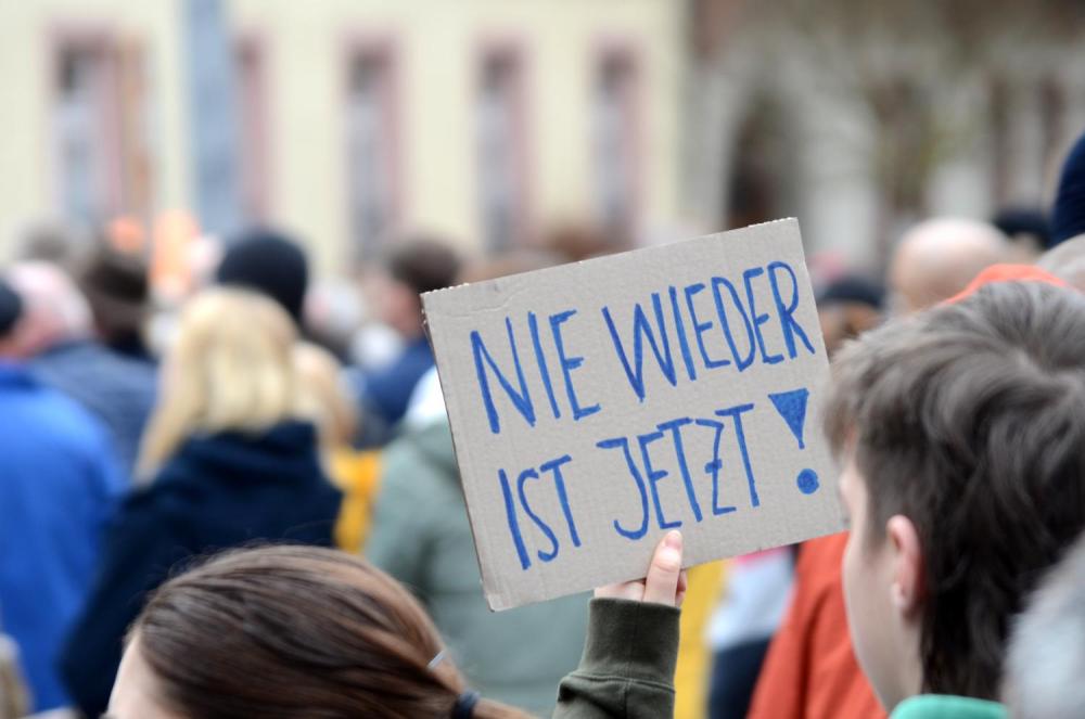 Ein Demonstrant hält ein Schild: "Nie wieder ist jetzt!"